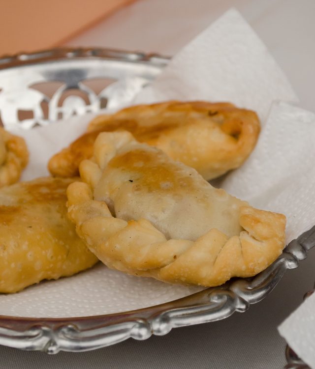 Empanada abierta sobre plato de plata, foco corto