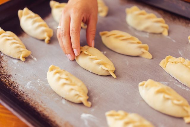 Mano acomodando empanadas antes del horno